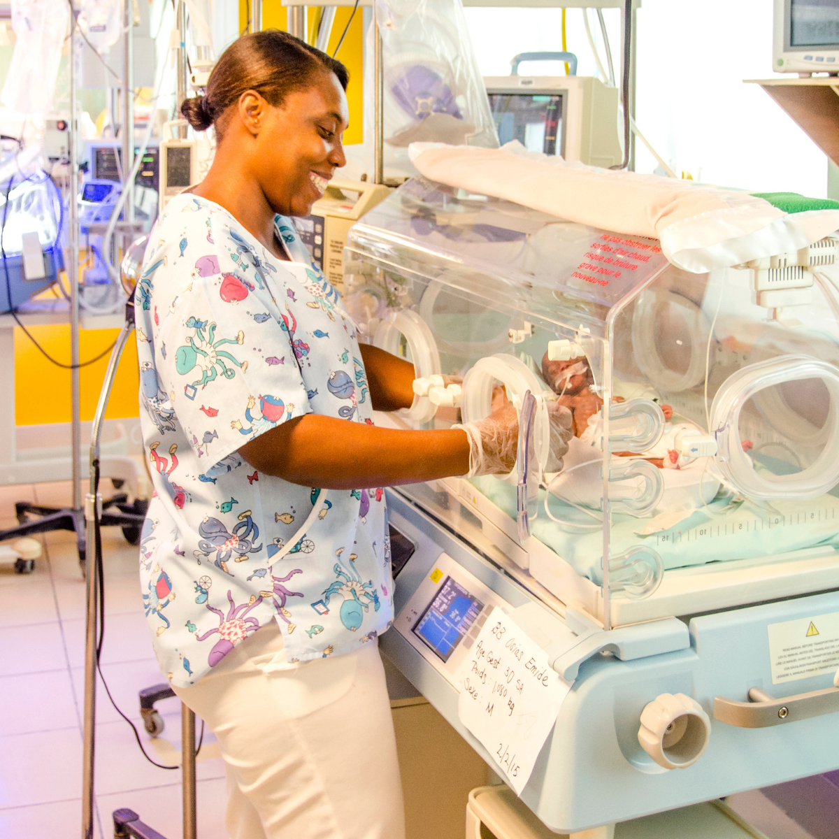 Een zorgverlener verzorgt een pasgeboren baby in een couveuse in kinderziekenhuis St. Damien in Haïti.